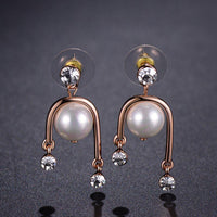 Side angle view of KHAISTA geometric pearl rhinestone dangle earrings