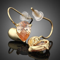 Close up of KHAISTA gold plated broken heart drop earrings