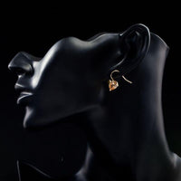 Side angle view of KHAISTA gold plated broken heart drop earrings