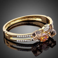 Side angle view of KHAISTA gold plated caramel crystal bangle