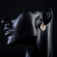 Side angle view of KHAISTA gold plated light peach crystal heart earrings