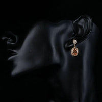 Side angle view of KHAISTA gold plated caramel CZ drop earrings