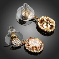Close up of KHAISTA gold plated caramel CZ drop earrings