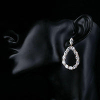 Side angle view of KHAISTA gold plated CZ chain drop earrings