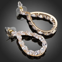 Close up of KHAISTA gold plated CZ chain drop earrings
