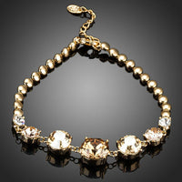 KHAISTA gold plated CZ charm bracelet on white background