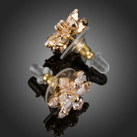 Close up of KHAISTA gold plated CZ flower shaped stud earrings