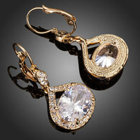 Close up of KHAISTA gold plated CZ love drop earrings