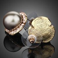 Close up of KHAISTA gold plated dome shaped stud earrings