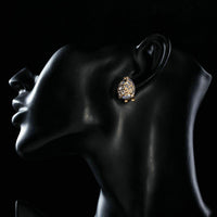 Side angle view of KHAISTA gold plated flower shaped CZ earrings