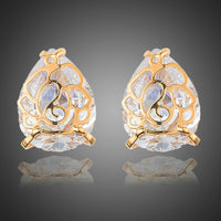 KHAISTA gold plated flower shaped CZ earrings on white background