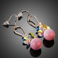 Close up of KHAISTA gold plated gradient pink drop earrings