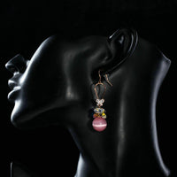 Side angle view of KHAISTA gold plated gradient pink drop earrings