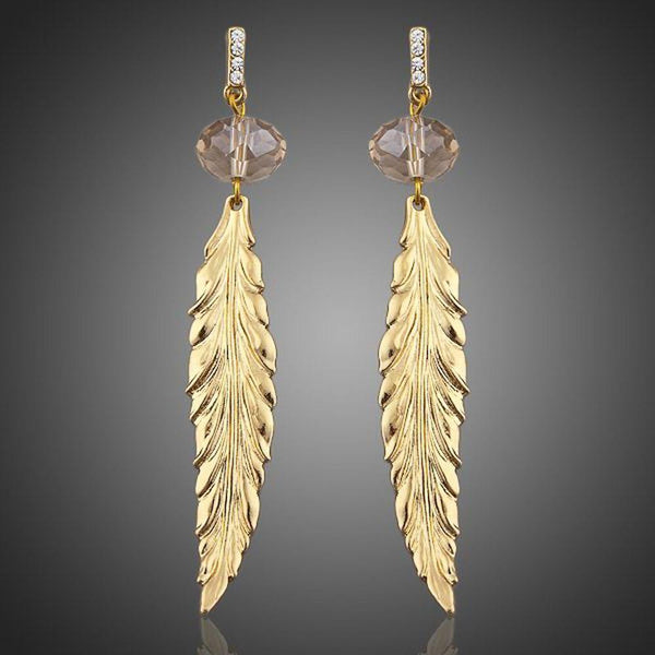 KHAISTA gold plated leaf drop earrings on white background