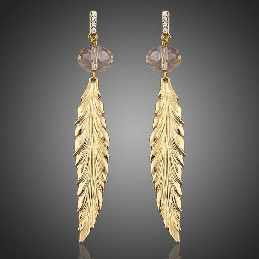 KHAISTA gold plated leaf drop earrings on white background
