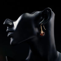 Side angle view of KHAISTA gold plated maple leaf design drop earrings