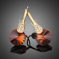 Close up of KHAISTA gold plated maple leaf design drop earrings