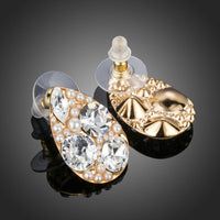 Close up of KHAISTA gold plated pear cut stud earrings