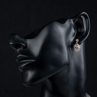 Side angle view of KHAISTA gold plated prolate crystal drop earrings