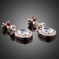 Close up of KHAISTA gold plated prolate crystal drop earrings