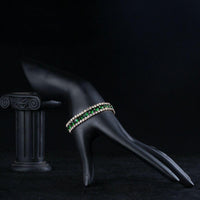 Side angle view of KHAISTA gold plated round green crystal bracelet