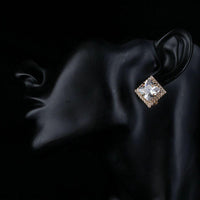 Side angle view of KHAISTA gold plated square CZ stud earrings