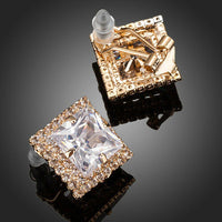 Close up of KHAISTA gold plated square CZ stud earrings