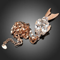 Side angle view of KHAISTA gold crystal fish pendant necklace