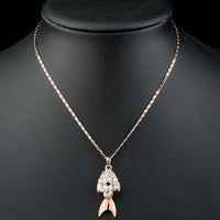 Close up detail of KHAISTA gold crystal fish pendant necklace