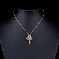 Close up detail of KHAISTA gold crystal key pendant necklace