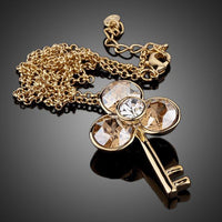 Side angle view of KHAISTA gold crystal key pendant necklace