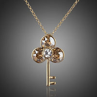 KHAISTA gold crystal key pendant necklace on white background