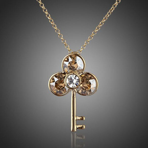KHAISTA gold crystal key pendant necklace on white background
