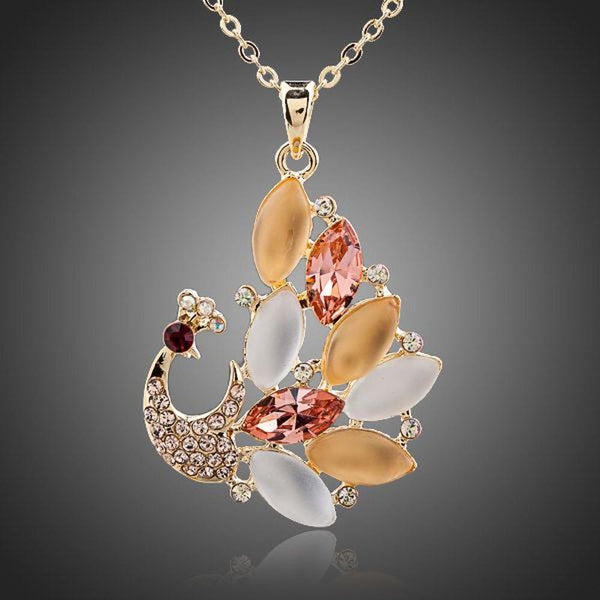 KHAISTA gold crystal peacock pendant necklace on white background