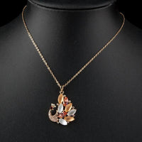 Close up detail of KHAISTA gold crystal peacock pendant necklace