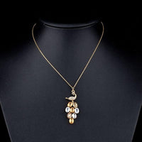 Close up detail of KHAISTA gold crystal peacock train pendant necklace