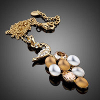 Side angle view of KHAISTA gold crystal peacock train pendant necklace