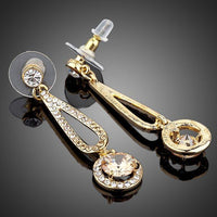 Side angle view of KHAISTA golden round CZ drop earrings