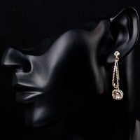 Close up of KHAISTA golden round CZ drop earrings