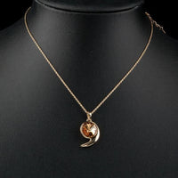Side angle view of KHAISTA gold crystal snail link chain necklace