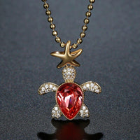 Close up detail of KHAISTA gold crystal tortoise pendant necklace
