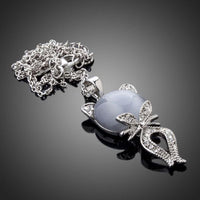 Side angle view of KHAISTA grey crystal cat pendant necklace