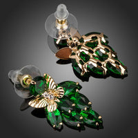Side angle view of KHAISTA green CZ butterfly drop earrings