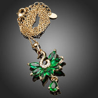 Side angle view of KHAISTA green crystal swan pendant necklace