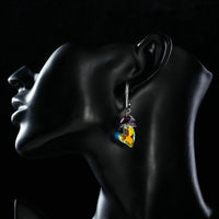 Side angle view of KHAISTA heart charm crystal drop earrings