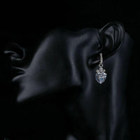 Close up of KHAISTA clear crystal heart drop earrings