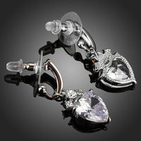 Side angle view of KHAISTA clear crystal heart drop earrings