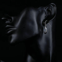 Side angle view of KHAISTA hook design CZ drop earrings