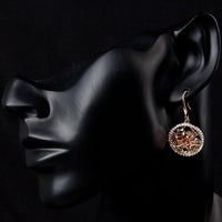 Close up of KHAISTA irregular gold CZ drop earrings