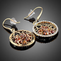 Side angle view of KHAISTA irregular gold CZ drop earrings